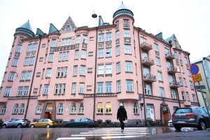Woman walking towards large fairytale like pink apartment building
