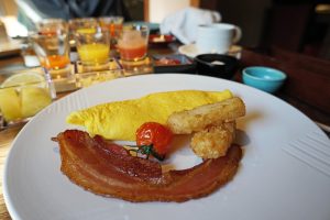 Breakfast spread at Suiran Kyoto eggs, tater tots and a slice of bacon with juice flight in the background