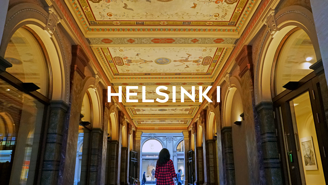image of passageway with ceiling lights and woman with Helsinki word written on top