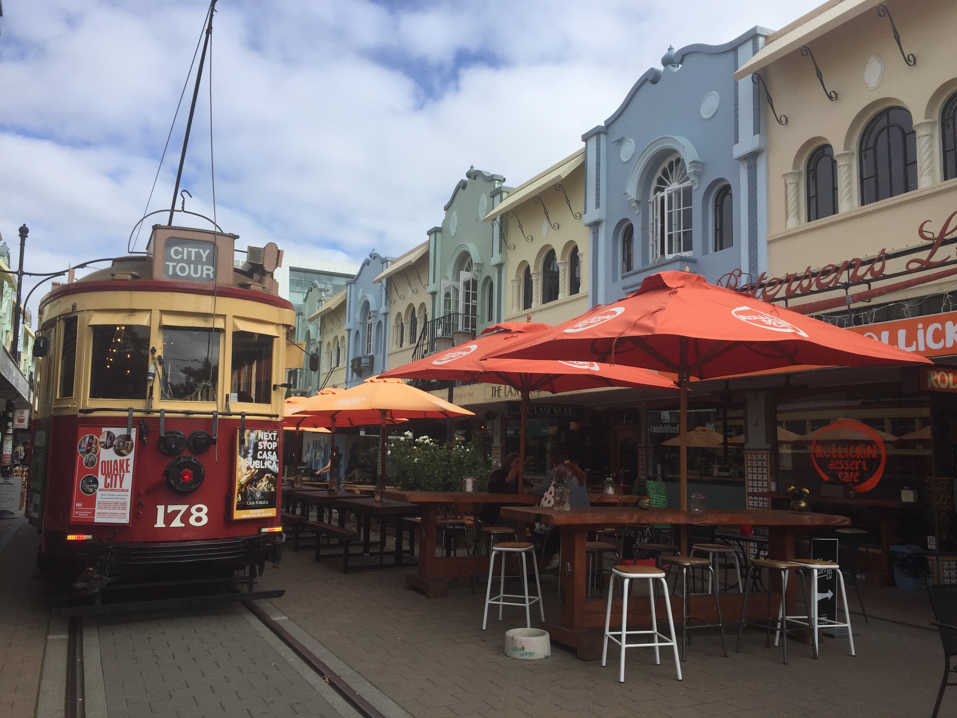 Christchurch New Regent Street NZ cable car in front of colorful umbrellas and houses