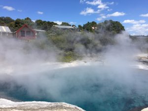 Rotorua Whakarewareawa NZ top destination hot springs steam over blue water in front of red house