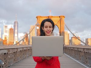 Brooklyn Bridge NYC laptop girl in red on computer video editing