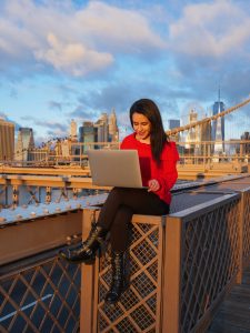 Brooklyn Bridge NYC laptop girl in red on computer video editing