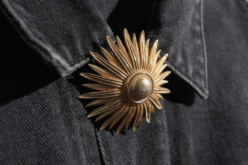 brooch travel gold costume jewelry on black denim jean jacket