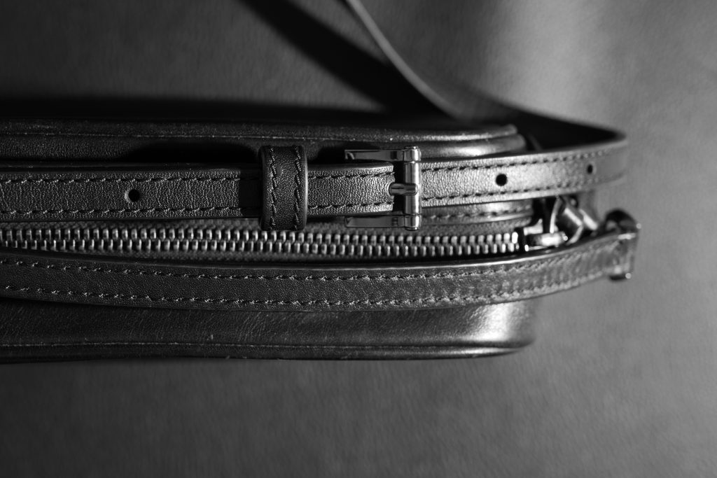 black purse strap zipper top down on black background